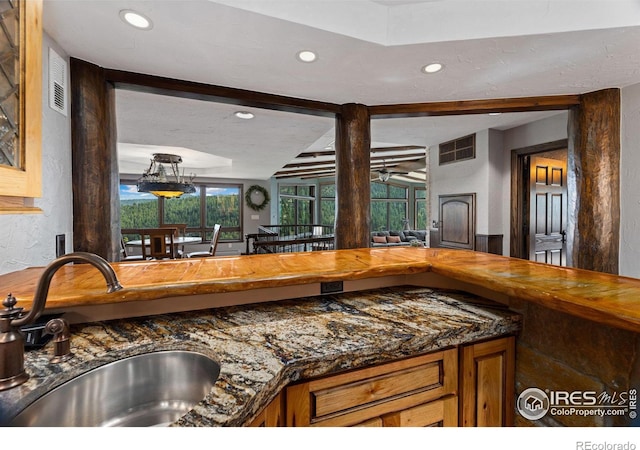 kitchen featuring beam ceiling, dark countertops, recessed lighting, visible vents, and a sink