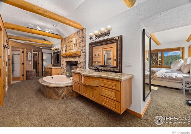 bathroom with a textured ceiling, lofted ceiling with beams, connected bathroom, a fireplace, and vanity