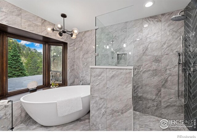 bathroom featuring a freestanding bath, walk in shower, tile walls, and an inviting chandelier