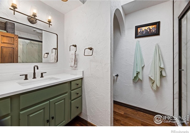 full bath featuring a textured wall, wood finished floors, and vanity