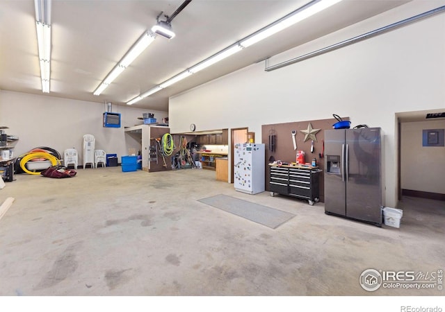 garage with stainless steel fridge with ice dispenser and a workshop area