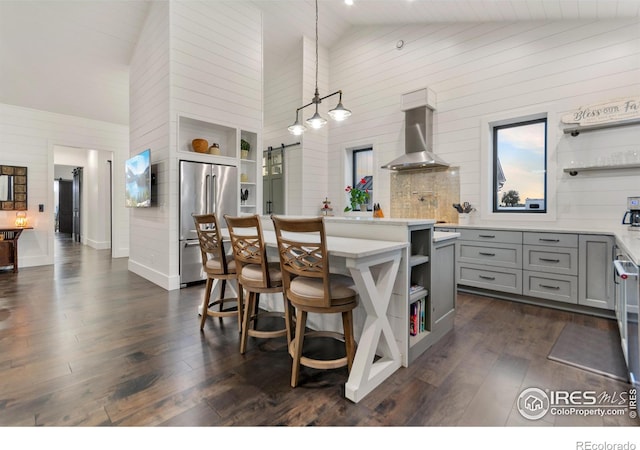 kitchen with a center island, a barn door, decorative light fixtures, high quality fridge, and wall chimney exhaust hood