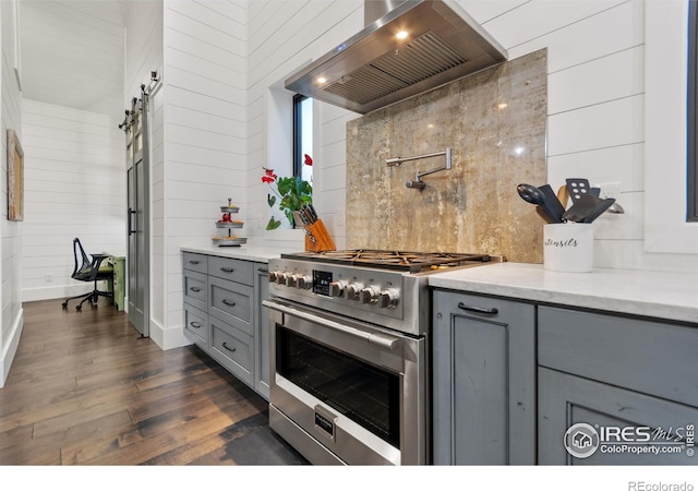 kitchen with custom exhaust hood, dark hardwood / wood-style flooring, light stone counters, high end stainless steel range, and gray cabinetry