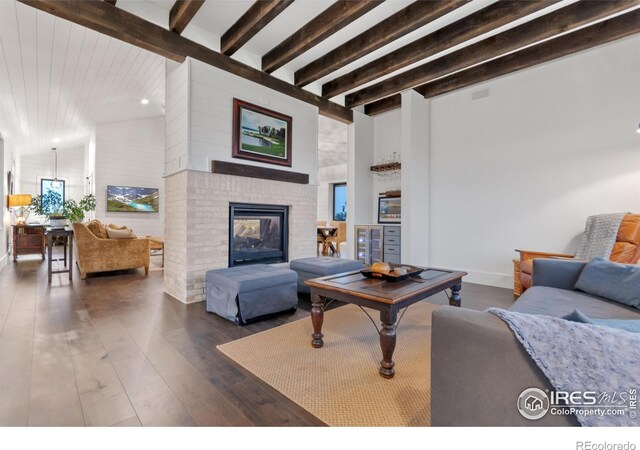 living room with dark wood-type flooring, beamed ceiling, and a brick fireplace