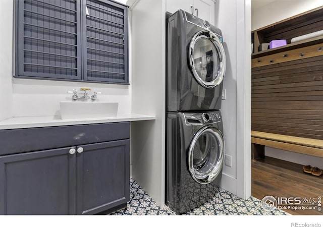 laundry room with cabinets, stacked washer and clothes dryer, and sink