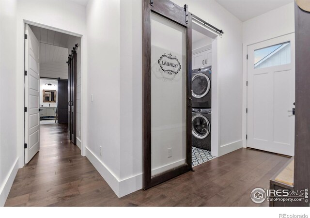 entrance foyer featuring a barn door, stacked washing maching and dryer, and hardwood / wood-style floors