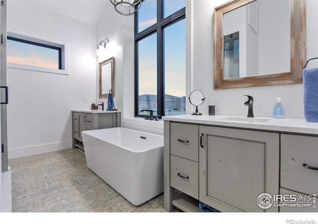 bathroom featuring vanity, vaulted ceiling, and a washtub