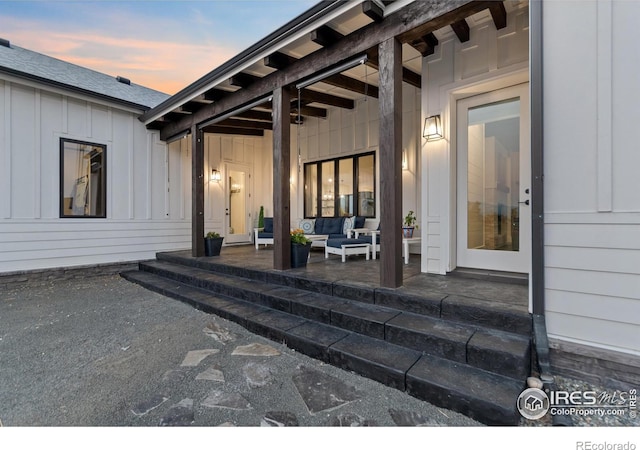 exterior entry at dusk with an outdoor living space and a patio