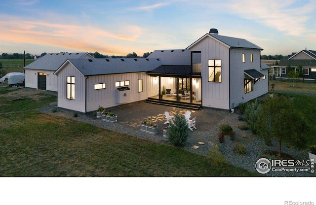 modern farmhouse style home with an outbuilding, a garage, a patio area, and a lawn