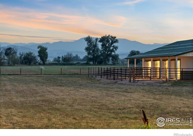 yard at dusk featuring a mountain view, a rural view, and an outdoor structure