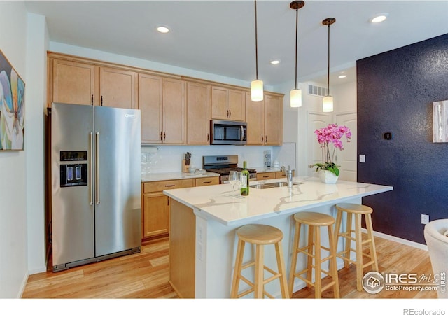 kitchen featuring light hardwood / wood-style flooring, backsplash, a kitchen island with sink, appliances with stainless steel finishes, and sink