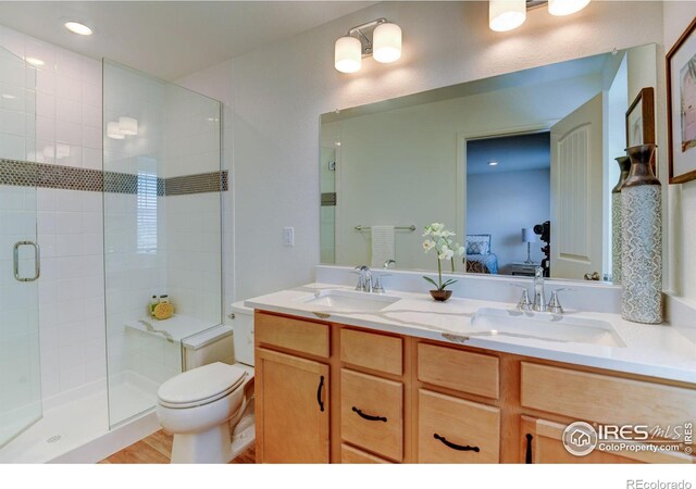 bathroom featuring dual vanity, toilet, walk in shower, and hardwood / wood-style floors