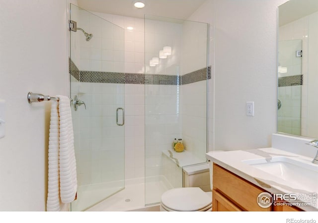 bathroom with vanity, a shower with door, and toilet