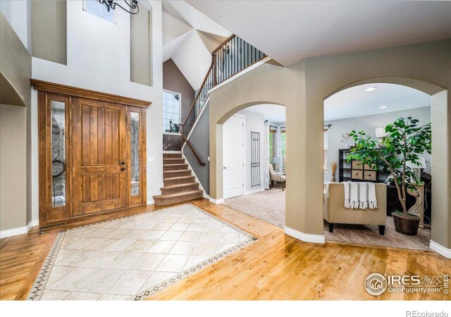 foyer entrance featuring a healthy amount of sunlight, a towering ceiling, and hardwood / wood-style floors