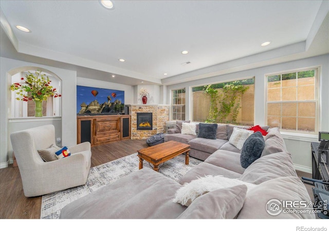 living room featuring hardwood / wood-style flooring, a raised ceiling, and a fireplace