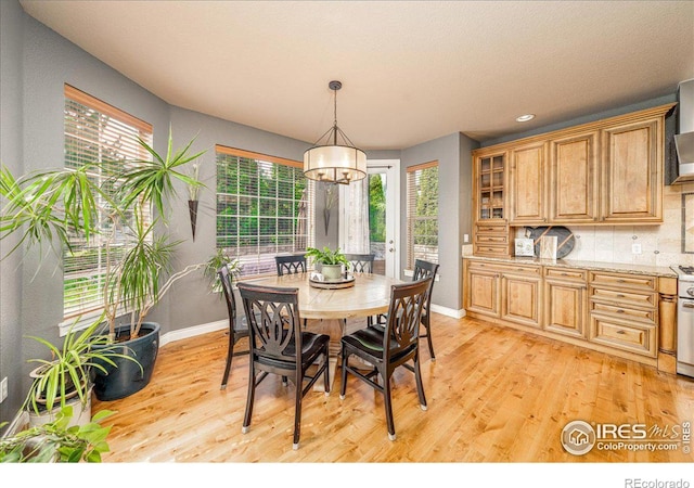 dining area with light wood-type flooring, an inviting chandelier, and a wealth of natural light