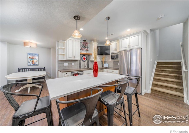 kitchen featuring appliances with stainless steel finishes, decorative backsplash, pendant lighting, sink, and white cabinetry