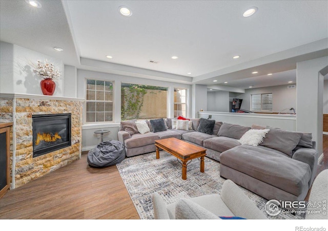 living room featuring hardwood / wood-style floors and a stone fireplace