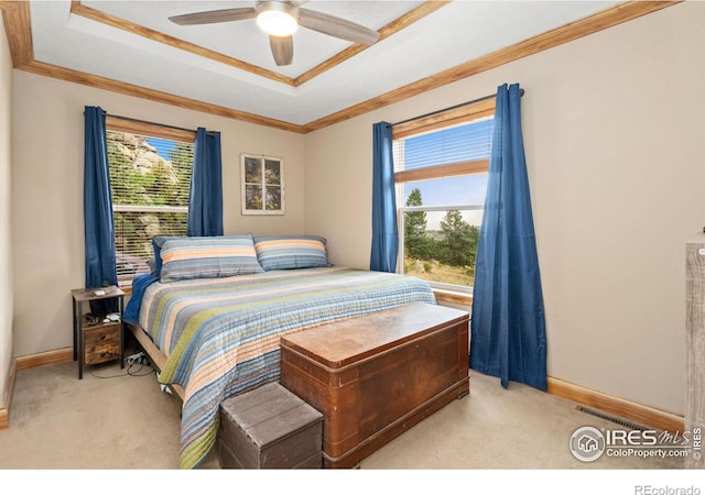 carpeted bedroom with a tray ceiling, ornamental molding, and ceiling fan