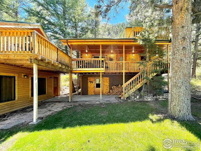 back of house featuring a patio, a yard, and a wooden deck