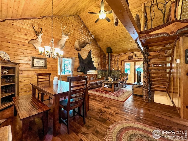 dining area featuring ceiling fan with notable chandelier, a wood stove, hardwood / wood-style floors, and wood ceiling