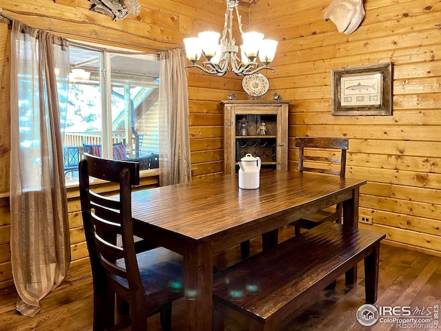 dining room featuring a chandelier, wooden walls, and wood-type flooring