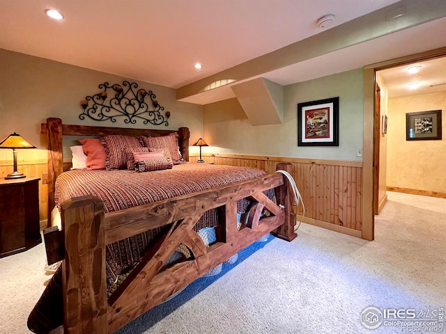 carpeted bedroom featuring wood walls