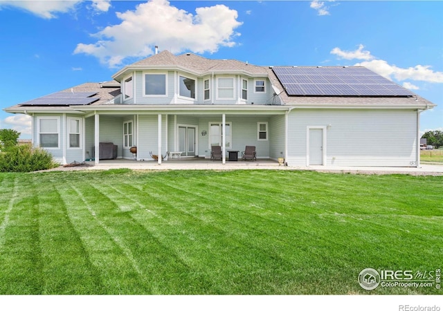 rear view of house with a patio area, a yard, and solar panels