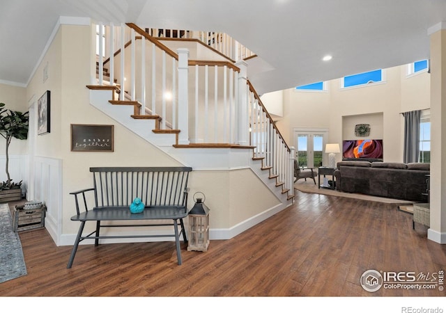 staircase with hardwood / wood-style flooring, a towering ceiling, and crown molding