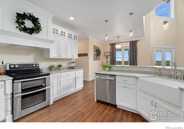 kitchen with stainless steel appliances, sink, hanging light fixtures, white cabinetry, and hardwood / wood-style flooring