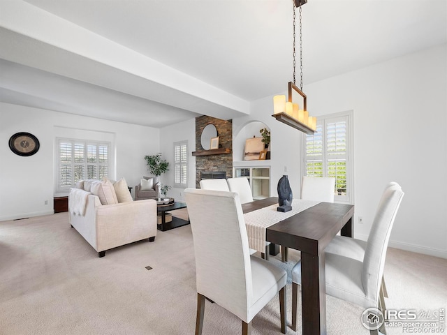 carpeted dining room with a stone fireplace and a wealth of natural light