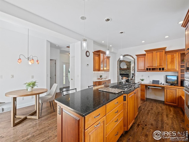 kitchen featuring dark hardwood / wood-style flooring, decorative light fixtures, a center island, and dark stone countertops