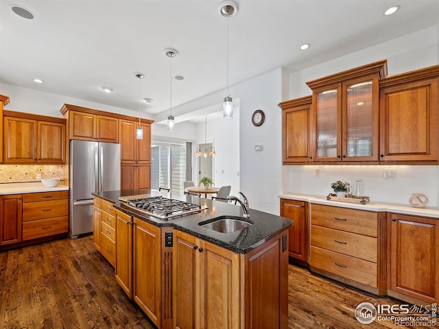 kitchen with pendant lighting, sink, appliances with stainless steel finishes, a kitchen island with sink, and dark hardwood / wood-style flooring