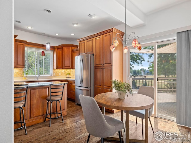 kitchen with stainless steel refrigerator, backsplash, dark hardwood / wood-style floors, and pendant lighting