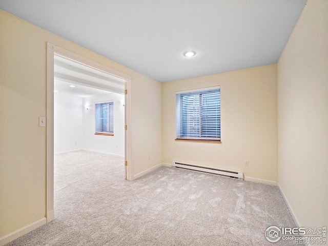 carpeted spare room featuring a baseboard heating unit