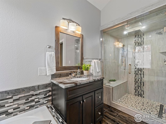 bathroom featuring vanity, hardwood / wood-style flooring, vaulted ceiling, and walk in shower