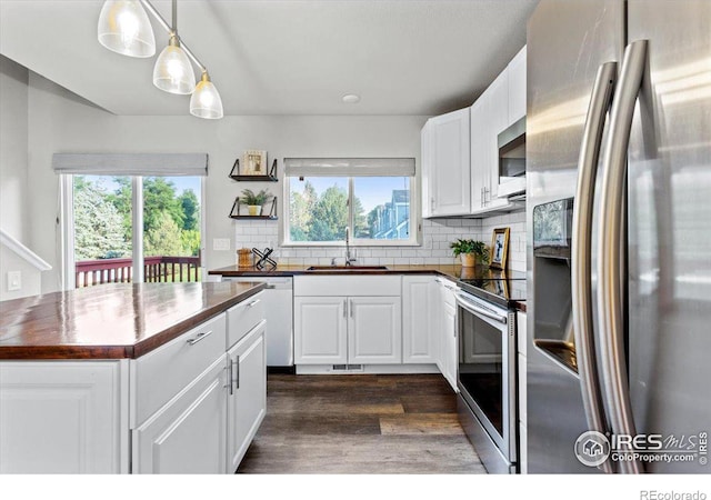 kitchen featuring butcher block countertops, sink, hanging light fixtures, stainless steel appliances, and white cabinets