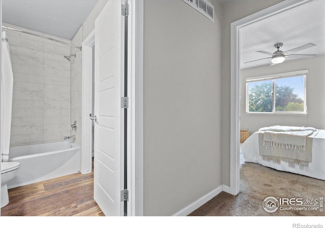 bathroom with tiled shower / bath combo, hardwood / wood-style floors, ceiling fan, and toilet