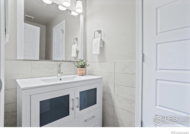 bathroom with vanity and tile walls