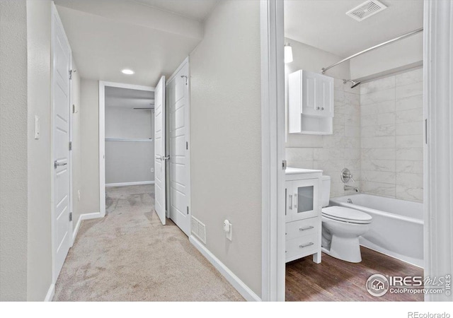 bathroom featuring tiled shower / bath, toilet, and hardwood / wood-style floors