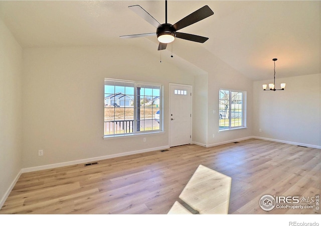 unfurnished room featuring ceiling fan with notable chandelier, light hardwood / wood-style floors, and lofted ceiling