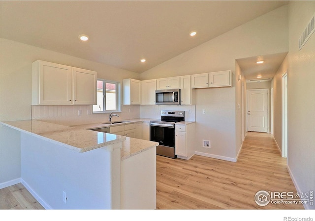 kitchen with lofted ceiling, stainless steel appliances, white cabinetry, and light hardwood / wood-style floors