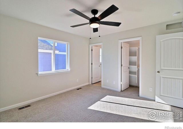 unfurnished bedroom featuring light carpet, a walk in closet, ceiling fan, connected bathroom, and a closet