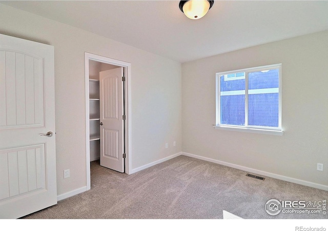 unfurnished bedroom with light carpet, a spacious closet, and a closet