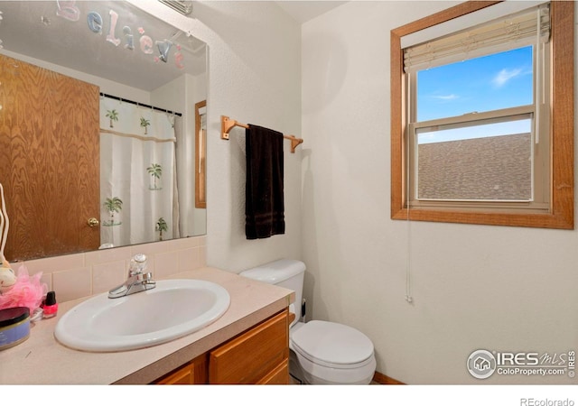 bathroom with backsplash, toilet, and vanity