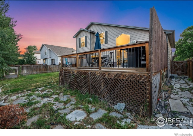 back house at dusk featuring a deck and a yard