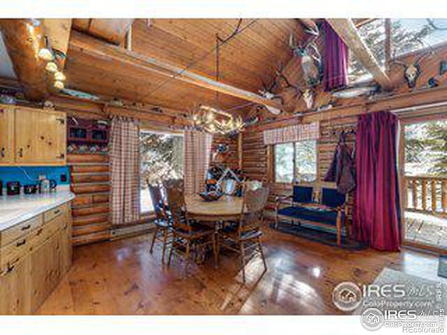 dining room with an inviting chandelier, log walls, light wood-type flooring, and wooden ceiling