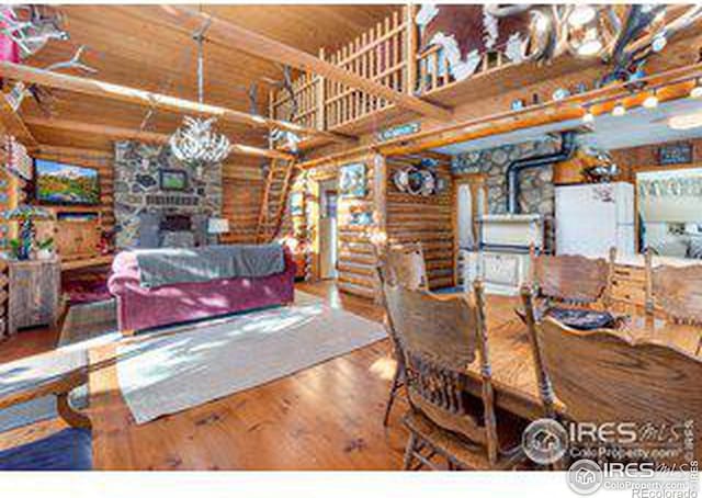 dining room featuring wooden ceiling, a wood stove, wood-type flooring, and rustic walls