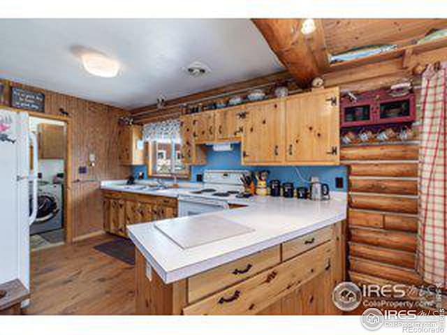 kitchen with log walls, kitchen peninsula, hardwood / wood-style flooring, and white range with electric stovetop