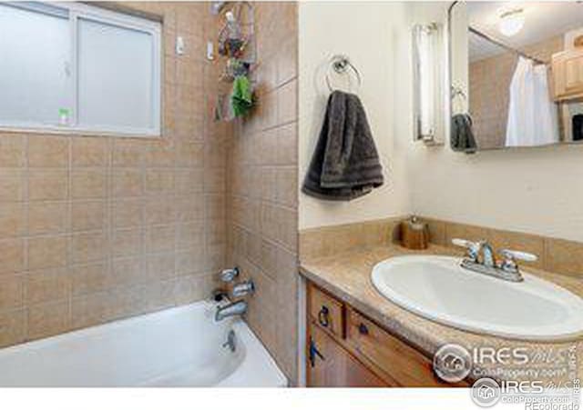 bathroom with tiled shower / bath combo and vanity